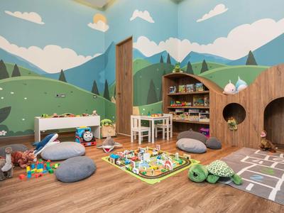Erkinder-Spielbereich mit bunten Spielzeugen und Naturwandmalerei in Holzinnenraum.