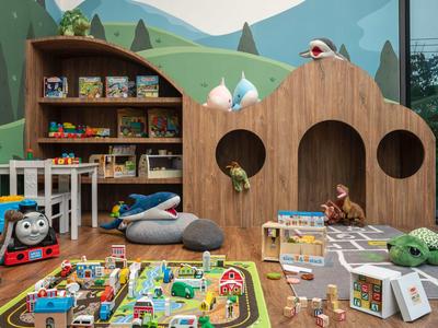 Bunter Kinderspielbereich mit Holzmöbeln, Spielzeugen und Plüschtiere in einem Hotel.