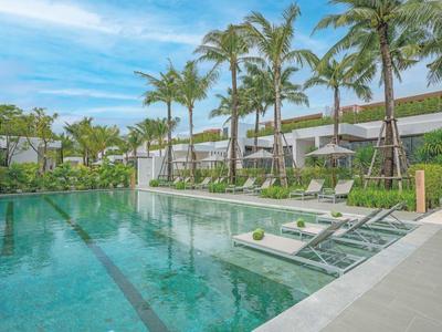 Nowoczesny basen z leżakami i palmami pod niebieskim niebem