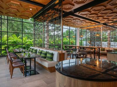 Offener, moderner Hotel-Loungebereich mit Holzmöbeln und grüner Außenansicht.