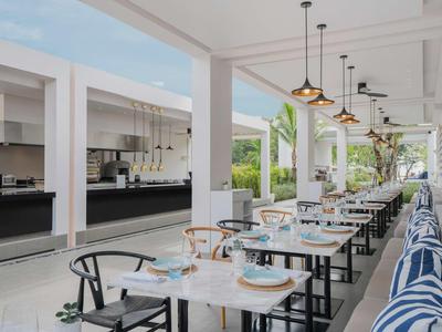 Nowoczesny taras z nakrytymi stołami i widokiem na otwartą kuchnię w hotelu.