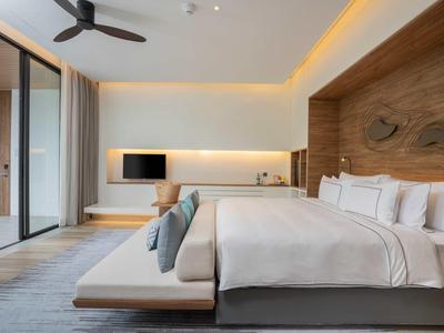 Habitación de hotel moderna con cama grande, banco lateral y fachada de vidrio a la veranda.