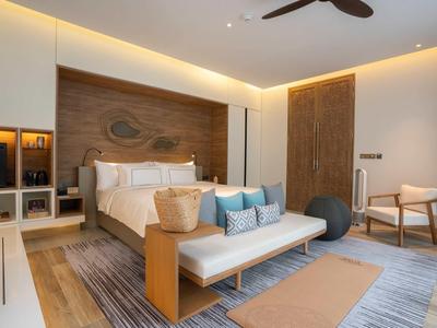 Modernes Schlafzimmer mit Holzakzenten, Doppelbett, Sofa, Teppichen und indirekter Beleuchtung.