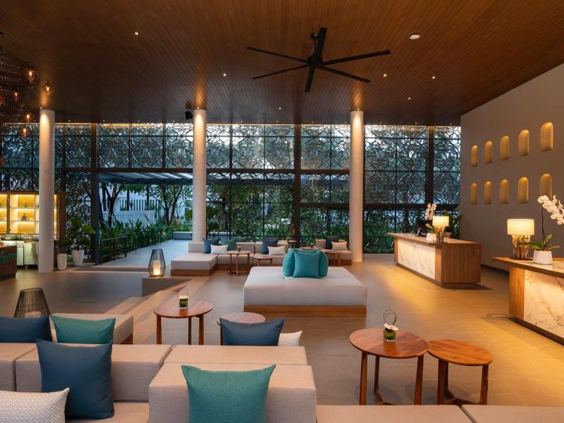 Habitación de hotel moderna con cómodos sofás y grandes ventanas con vistas a la naturaleza.