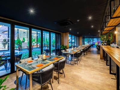 Ristorante moderno con lunghi tavoli, sedie e grandi finestre che si affacciano all'esterno.