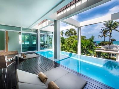 Piscine d'hôtel moderne avec chaises longues et vue sur les palmiers et le ciel bleu.