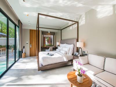 Helles Hotelzimmer mit Himmelbett, Sofa, Holzmöbeln und Zugang zum Pool