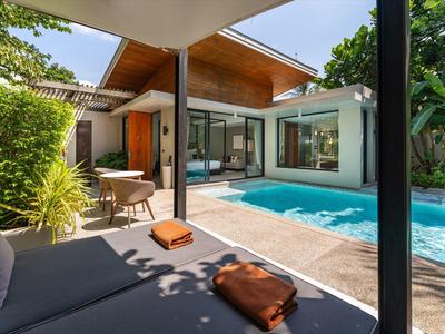 Moderner Außenbereich mit Pool, Sitzgelegenheiten und viel Grün in einem Hotelgarten.