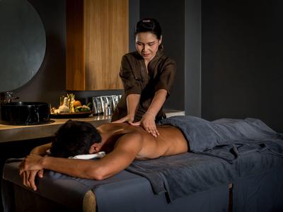 Person erhält Rückenmassage in einem stilvollen, gedämpft beleuchteten Spa-Raum.