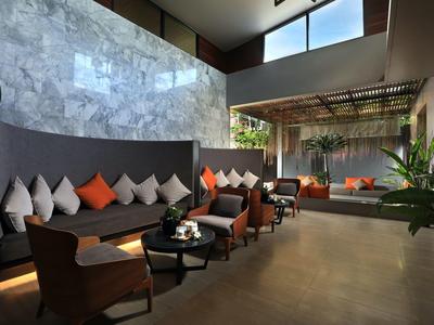 Moderner Lounge-Bereich mit grauen Sofas, orangefarbenen Kissen, Holzstühlen und großen Fenstern.