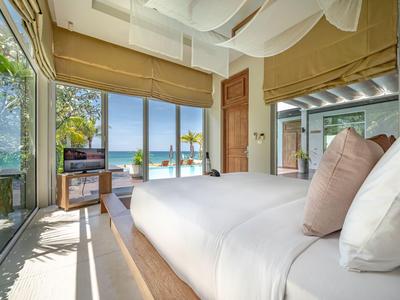 Helles Hotelzimmer mit großem Bett, Zugang zu einer Terrasse und Blick auf das Meer.