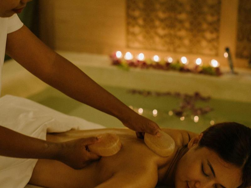 Donna che riceve un massaggio rilassante in una stanza spa con luce calda.