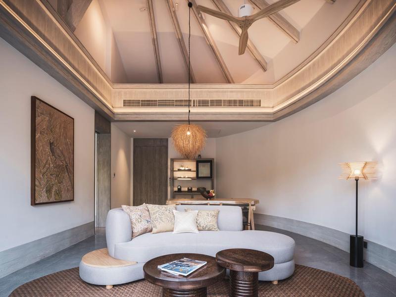 Soggiorno moderno con divano bianco, tavolini rotondi e grande quadro a parete.