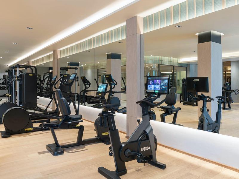 Palestra moderna con attrezzi cardio e grandi specchi in un hotel.