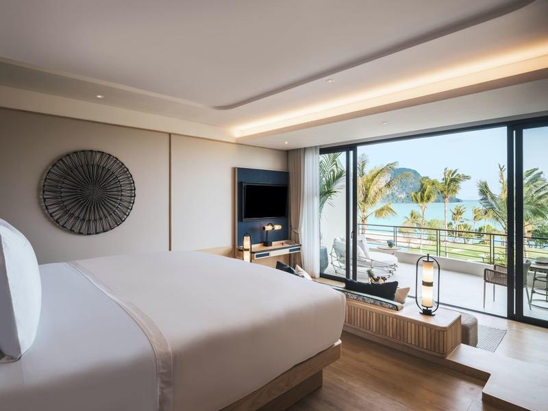 Camera d'hotel moderna con letto grande e vista su terrazza e mare.