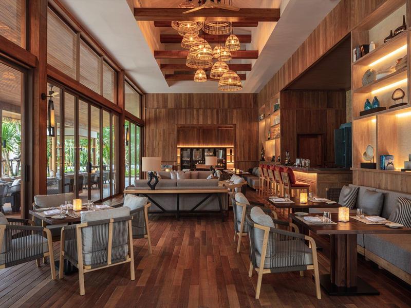 Elegante lounge dell'hotel con pavimenti in legno, aree salotto accoglienti e grandi finestre verso l'esterno.