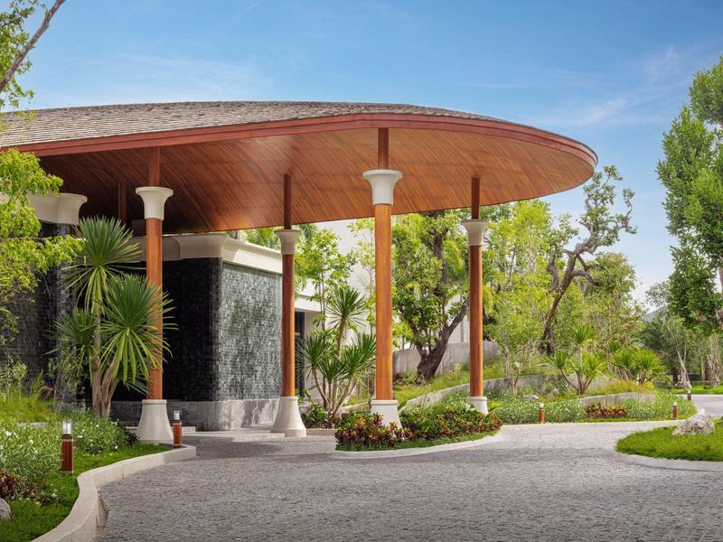 Area moderna dell'hotel con grande pensilina rotonda in legno e lussureggiante giardino.