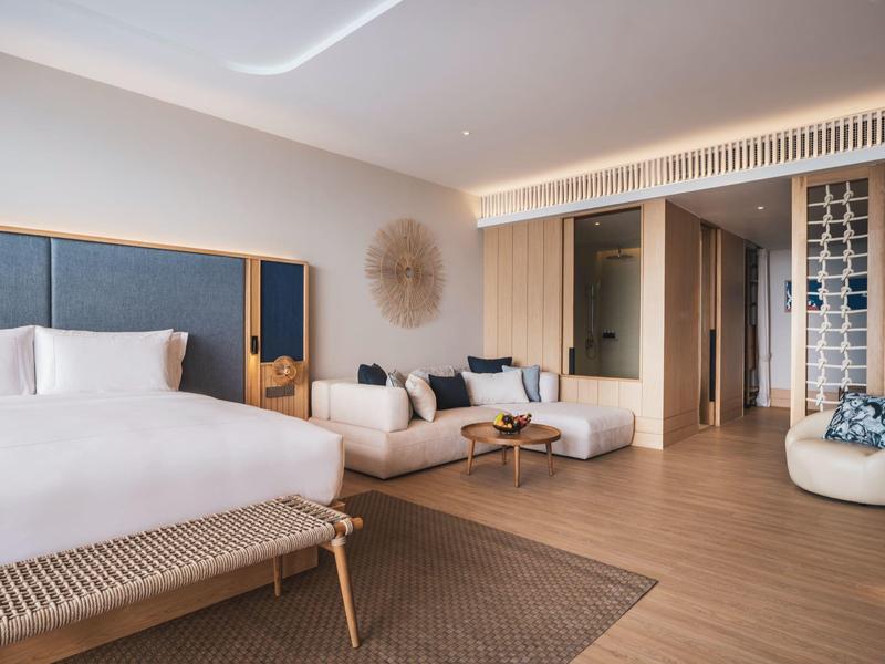 Camera d'hotel moderna con grande letto, divano e pavimento in legno.