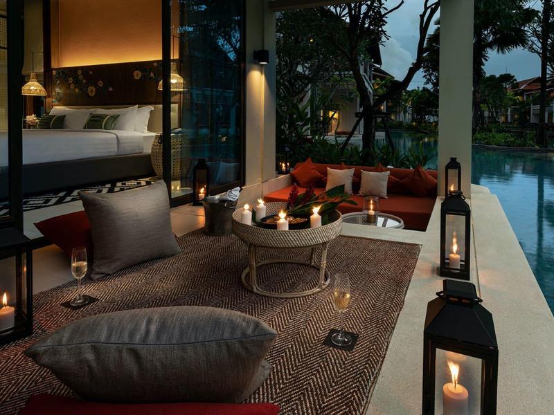 Večerní terasa s posezením vedle osvětleného bazénu v hotelu.