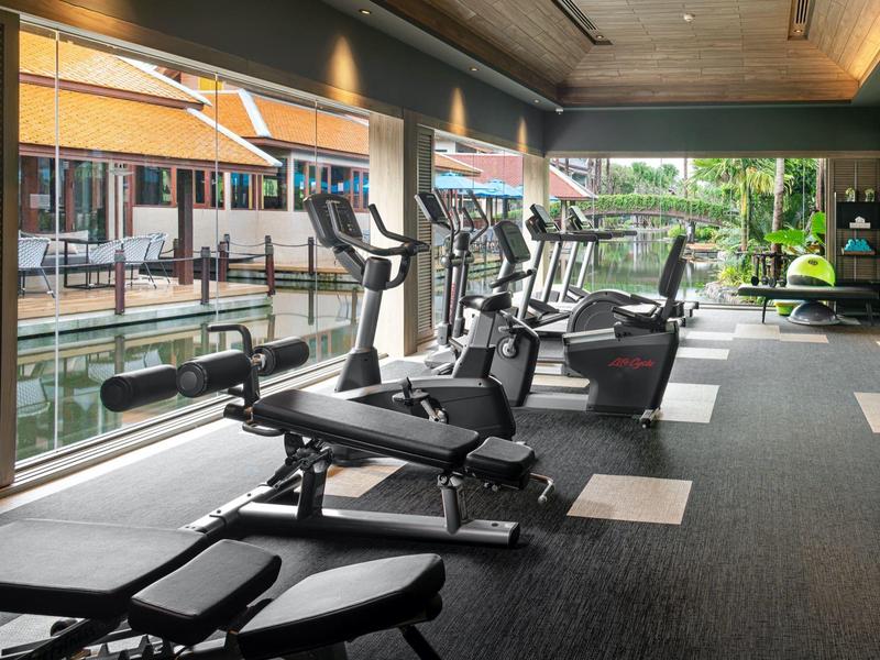 Moderní posilovna s vybavením a výhledem na vodu a terasu.