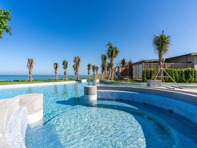 Čistý bazén s palmami a modrou oblohou vedle moderních budov.