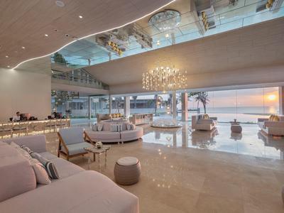 Moderní hotelový salon s velkými skleněnými okny s výhledem na západ slunce a moře.