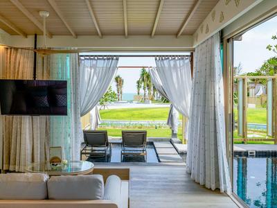 Výhled z pokoje se závěsy na terasu, posezení, zahradu a výhled na moře.