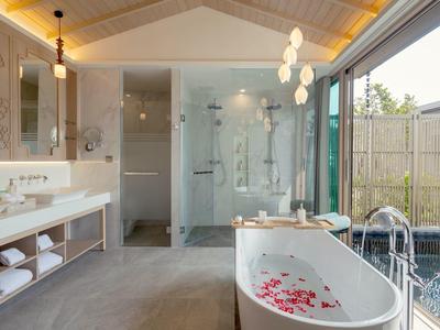 Moderní koupelna s volně stojící vanou, sprchou a velkým oknem s výhledem na zahradu.