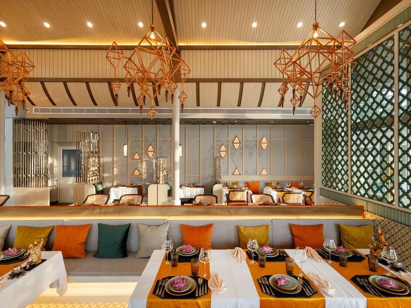 Modernes Restaurant mit weißen Tischen, dekorativen Lichtern und gemütlichen Sitzbereichen.