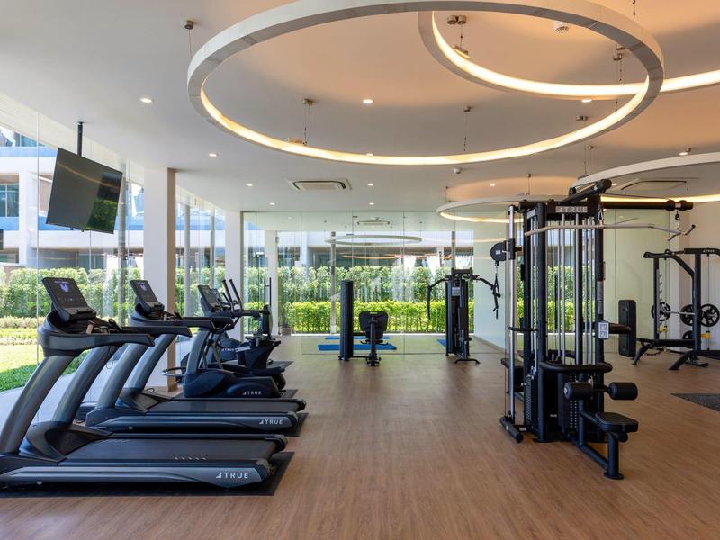 Světelná posilovna s moderním vybavením a velkými okny s výhledem ven.