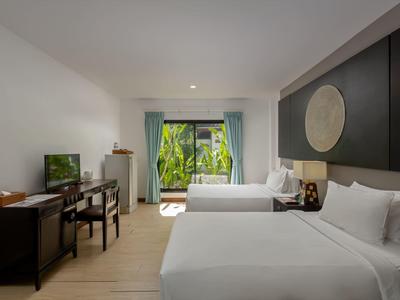 Modernes Hotelzimmer mit zwei Einzelbetten, Schreibtisch, TV und großem Fenster mit grüner Aussicht.