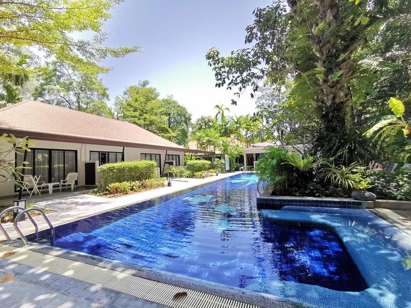 Piscina moderna dell'hotel accanto a bungalow in un ambiente tropicale rigoglioso.