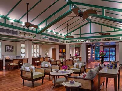 Großer Raum mit Holzfußboden, hohen Decken, Sesseln, Sofas und runden Tischen in warme Farbtönen.