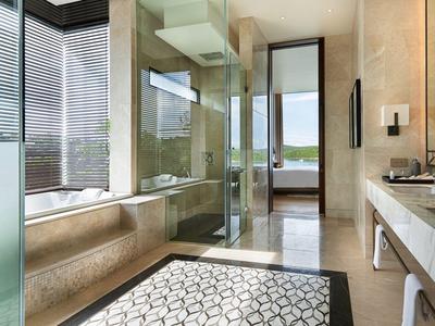 Helles Badezimmer mit großer Dusche, Marmorwaschbecken, Fensterfront und modernem Teppichmuster.