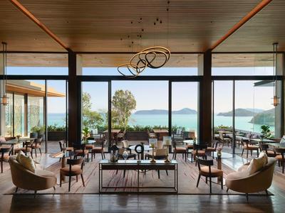 Moderner, heller Gastraum mit Holzdecken, großen Fenstern und Blick auf das Meer.