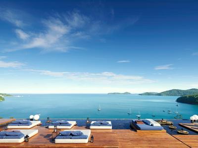 Luxuriöses Resort mit Liegestühlen auf einer Terrasse und Blick auf das blaue Meer.