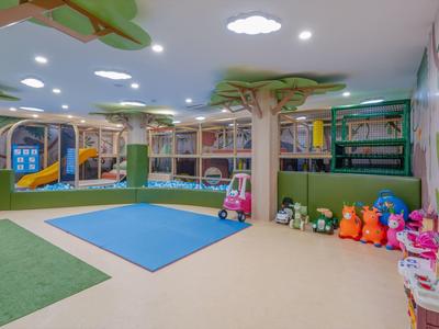 Hell beleuchteter, bunter Indoor-Spielbereich mit Rutschen, Klettergerüsten und Spielzeugen.