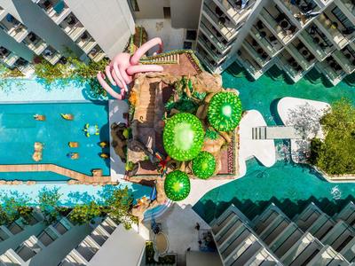 Luftaufnahme eines Hotels mit Poolbereich, Wasserwegen und grünen Pflanzen