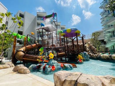 Spielplatz mit Wasserrutschen und bunter Ausstattung in einer Hotelanlage bei Sonnenschein.