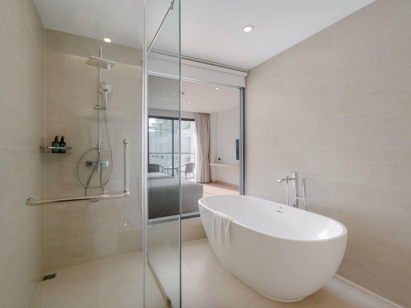 Helles Badezimmer mit freistehender Badewanne und begehbarer Dusche mit Glaswand.