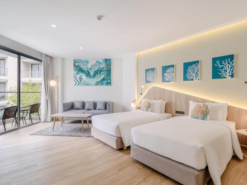 Modernes Hotelzimmer mit zwei Einzelbetten, Sofa, Balkon und dekorativer Wandbeleuchtung.