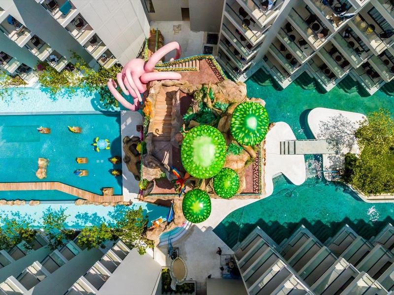 Luftaufnahme eines Hotels mit Poolbereich, Wasserwegen und grünen Pflanzen