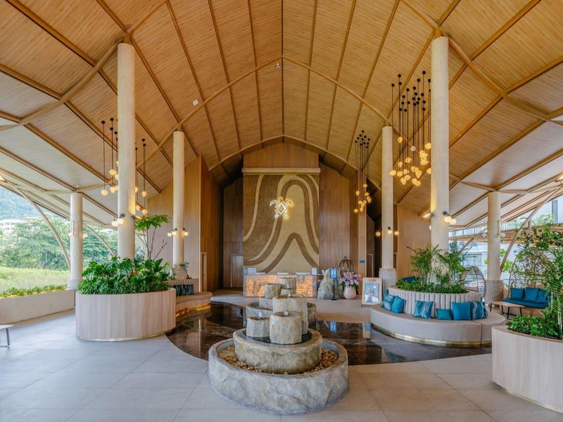 Elegante Hotellobby mit hohen Decken, Kamin, runden Pflanzenkübeln und modernem Design.