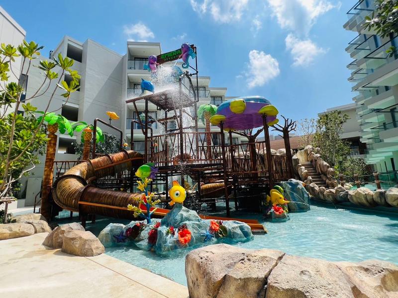 Spielplatz mit Wasserrutschen und bunter Ausstattung in einer Hotelanlage bei Sonnenschein.