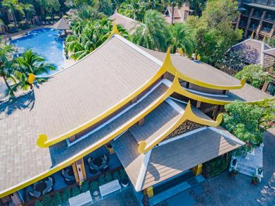 Vue aérienne d'un bâtiment avec un toit d'inspiration asiatique ponctué d'accents jaunes dans un cadre tropical.