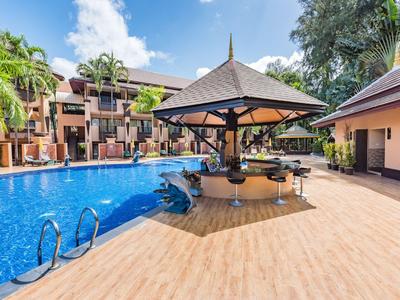 Grande piscine avec un parasol et un bar dans un cadre d'hôtel tropical.