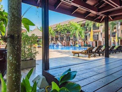 Blick auf einen Poolbereich eines Hotels mit Liegestühlen und Palmen unter einem Dach