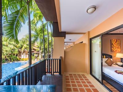 Balcon donnant sur une piscine et des plantes tropicales à côté d'une chambre d'hôtel.