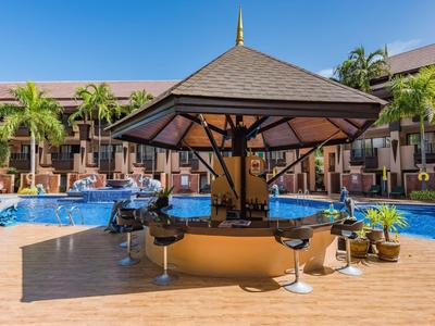 Poolbar mit runder Theke und Hockern an einem Hotelpool unter blauem Himmel