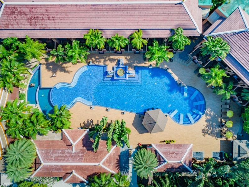 Vogelperspektive eines Hotelpools mit umliegenden Gebäuden und Palmen